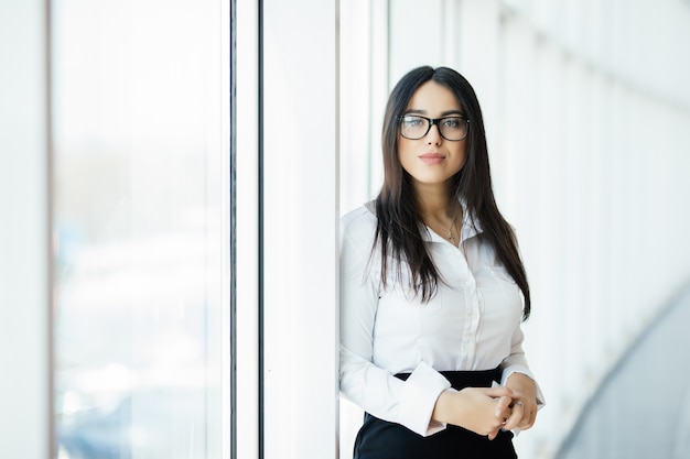 Businesswoman in glasses crossed hands portrait in office with panoramic windows. Business concept