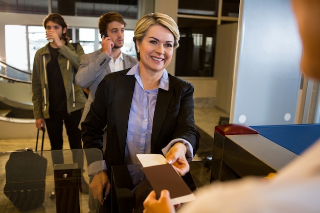 Free photo businesswoman handing over her boarding pass to the female staff