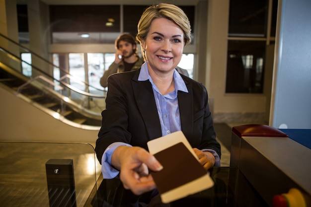 Businesswoman handing over his boarding pass at counter