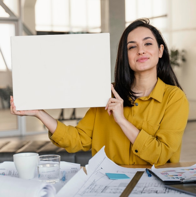 Donna di affari che tiene una scheda in bianco sul lavoro