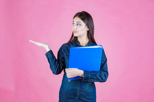 Businesswoman holding a blue folder and making presentation