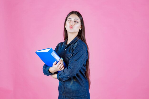 Businesswoman holding a blue folder and sending love