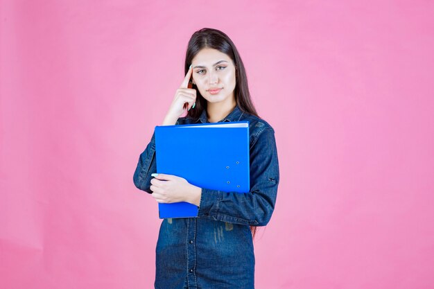 Businesswoman holding a blue folder and thinking