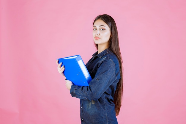 Free photo businesswoman holding a blue folder with self confidence