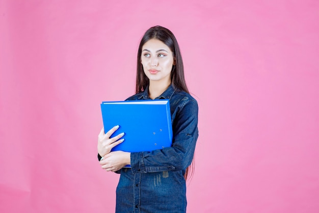 Businesswoman holding a blue folder with self confidence