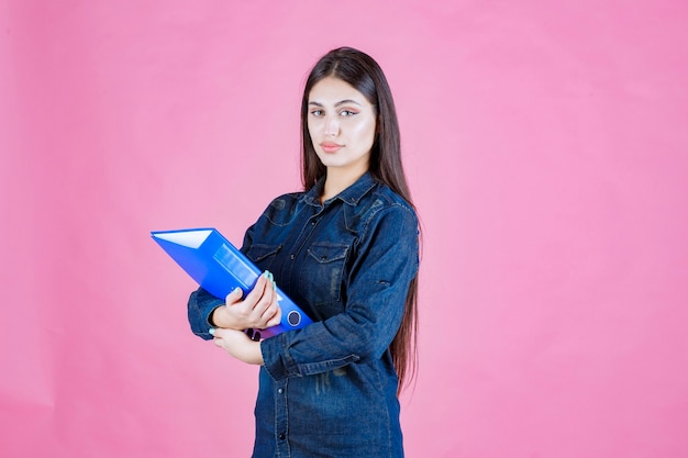 Businesswoman holding a blue folder with self confidence