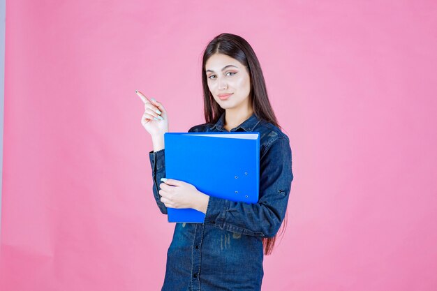 Businesswoman holding a blue report folder and pointing up