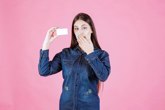 Businesswoman holding business card and covering her mouth