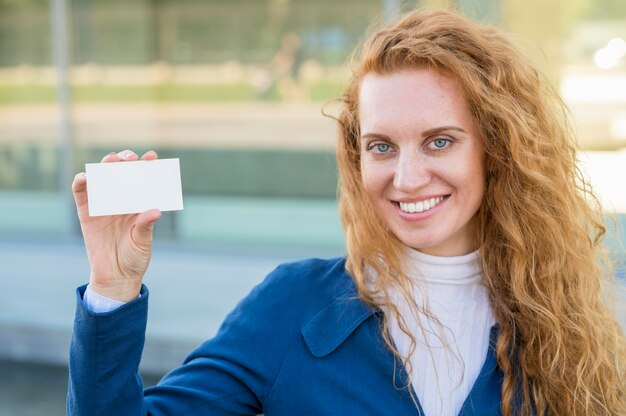Деловая женщина держит визитную карточку и улыбается
