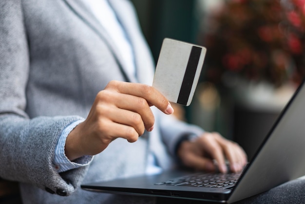 Free photo businesswoman holding credit card while using laptop