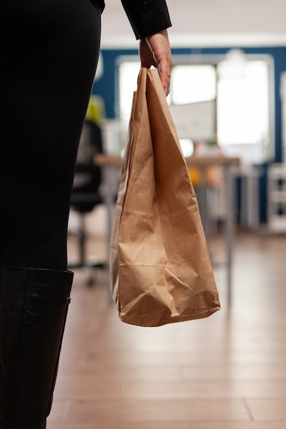 Деловая женщина держит бумажный пакет с доставкой на вынос еды и еды во время обеда на вынос