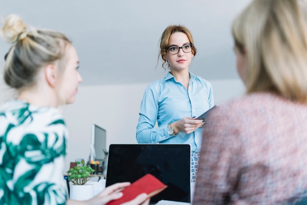 Free photo businesswoman holding digital tablet talking with her colleagues