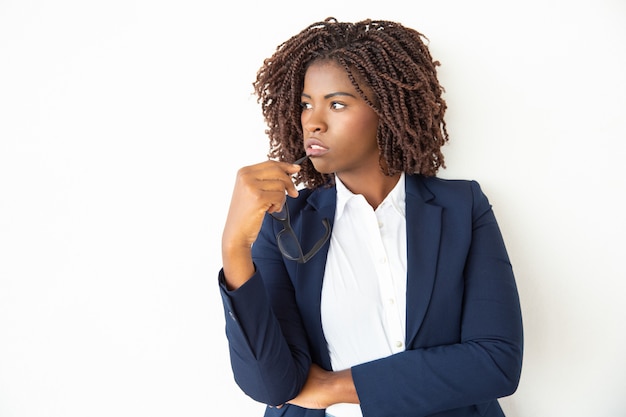 Businesswoman holding eyeglasses and looking aside