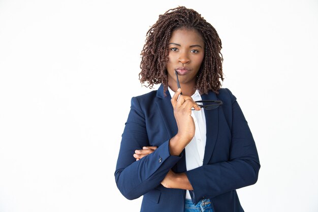 Businesswoman holding eyeglasses and looking at camera