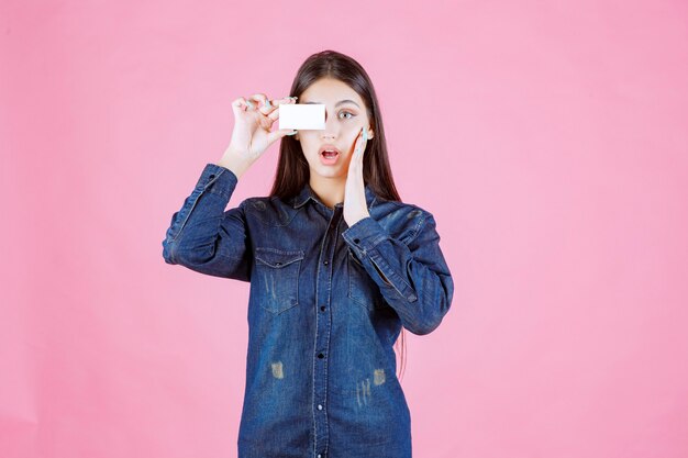 Businesswoman holding her business card to her eye