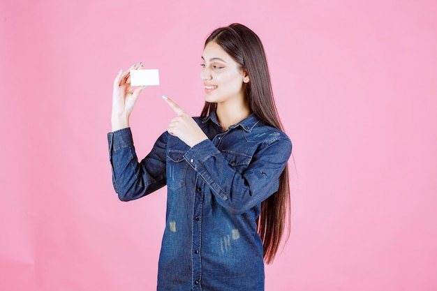 Free photo businesswoman holding and pointing at her business card