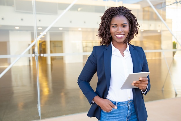 Businesswoman holding tablet pc and smiling at camera