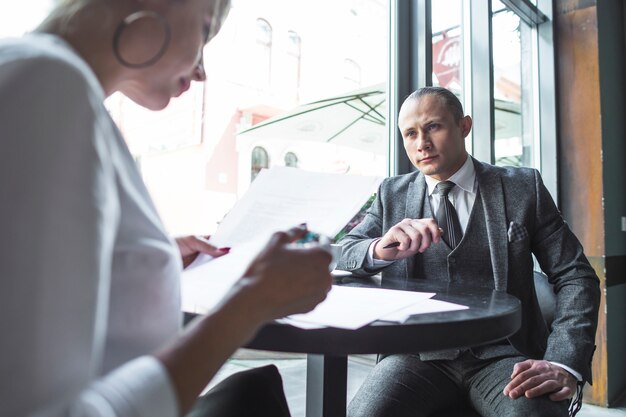 Businesswoman looking at his colleague examining document in caf�