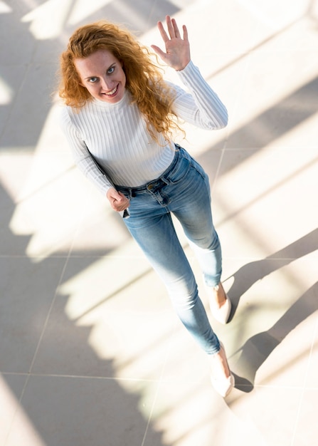 Businesswoman looking up and waving with her hand