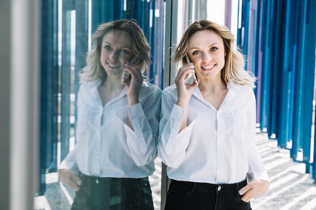 Free photo businesswoman making phone call next to windows