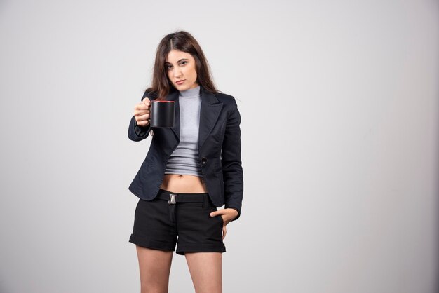 A businesswoman offering a cup of coffee or tea . 