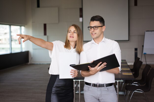 Businesswoman pointing direction to smiling male colleague. 