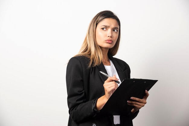 Businesswoman posing and holding clipboard. 