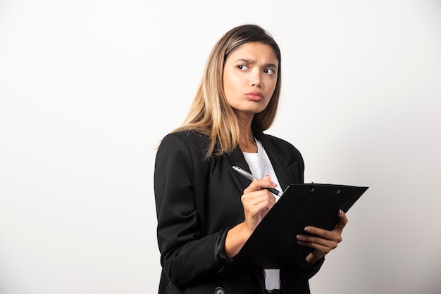 Businesswoman posing and holding clipboard. 