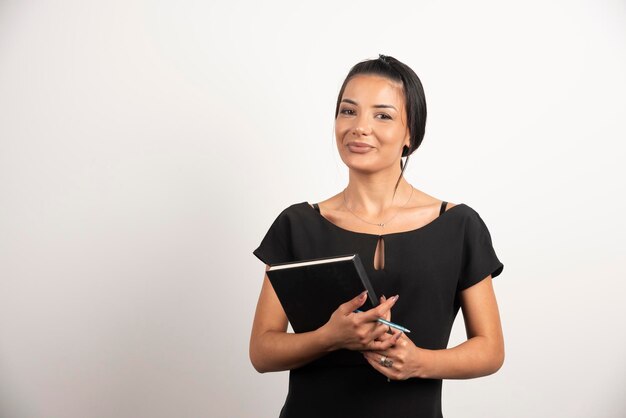 Free photo businesswoman posing with notebook on white wall.