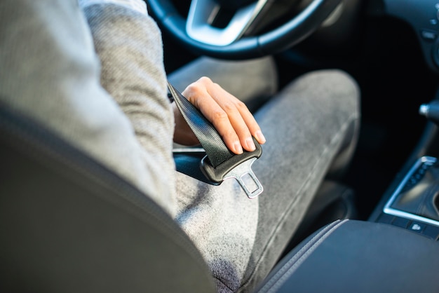 Businesswoman putting on the seat belt in the car