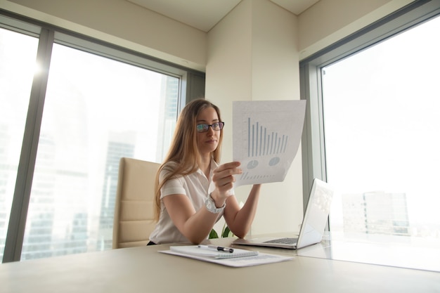 Businesswoman reading document with graphs