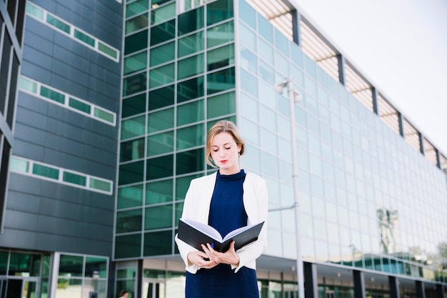 Businesswoman reading in front of building