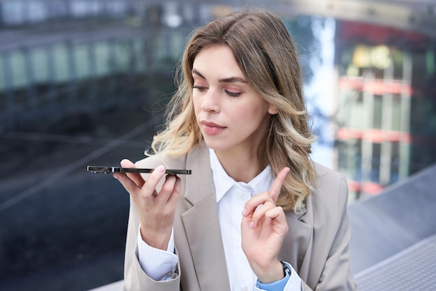 Free photo businesswoman records voice message dictating something on mobile phone making a note on smartphone