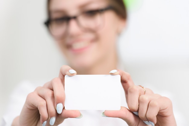 Businesswoman's hand showing blank white visiting card toward camera