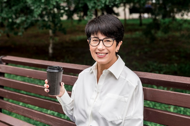 Businesswoman sitting on a bench and having a coffee