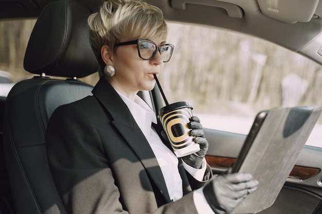 Businesswoman sitting inside a car and drinks a coffee