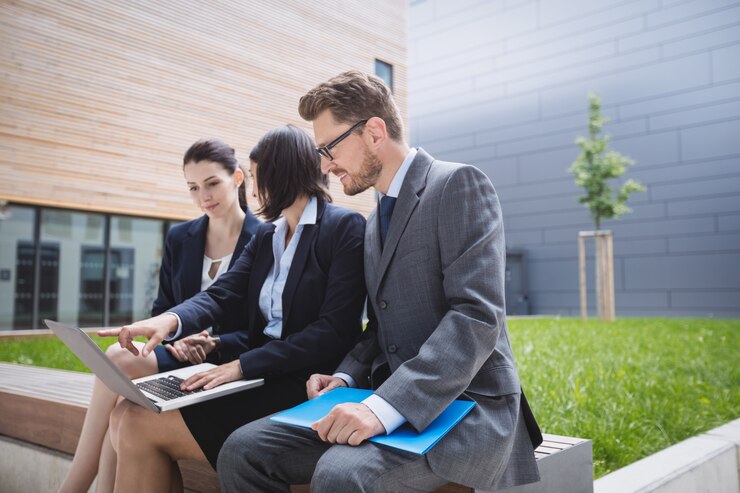 Free Photo businesswoman sitting with colleagues and using laptop