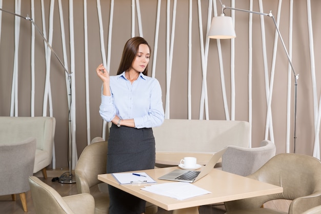 Businesswoman Standing at Cafe Table with Laptop