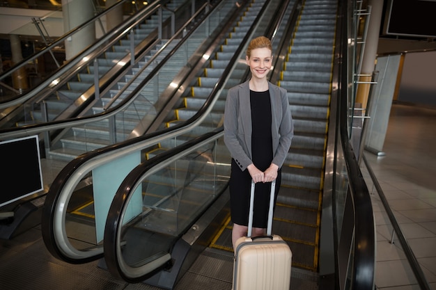 Businesswoman standing near escalator with luggage