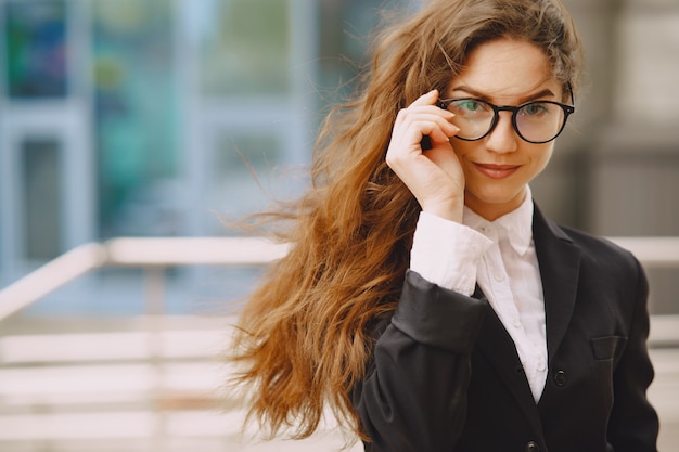 Foto gratuita donna di affari che sta all'aperto nell'edificio per uffici della città