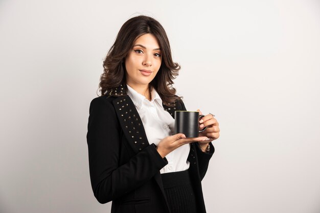 Businesswoman standing with cup of tea on white