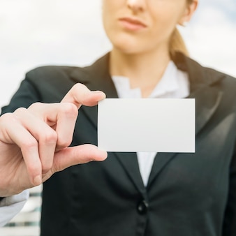 Businesswoman in suit showing blank white visit card