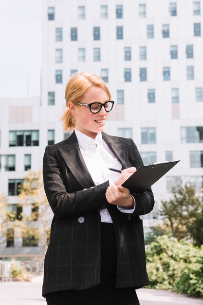 Businesswoman in suit writing on clipboard with pen