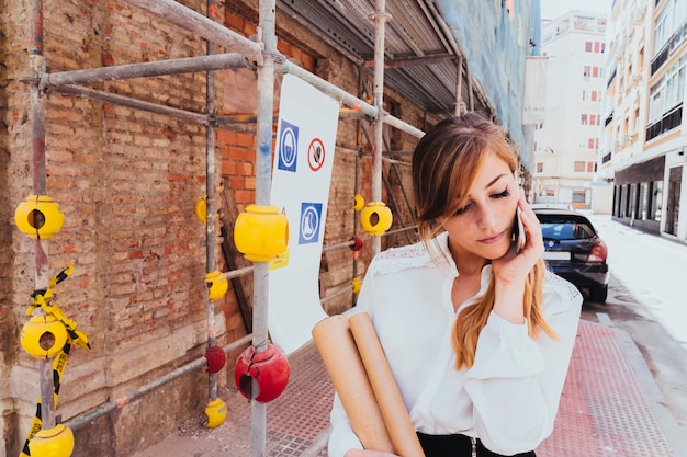 Businesswoman talkin on the phone with scaffold at the background