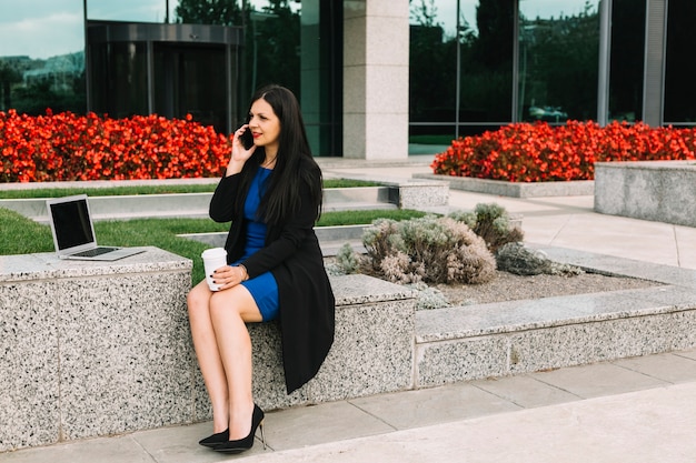 Businesswoman talking on cellphone outside office building