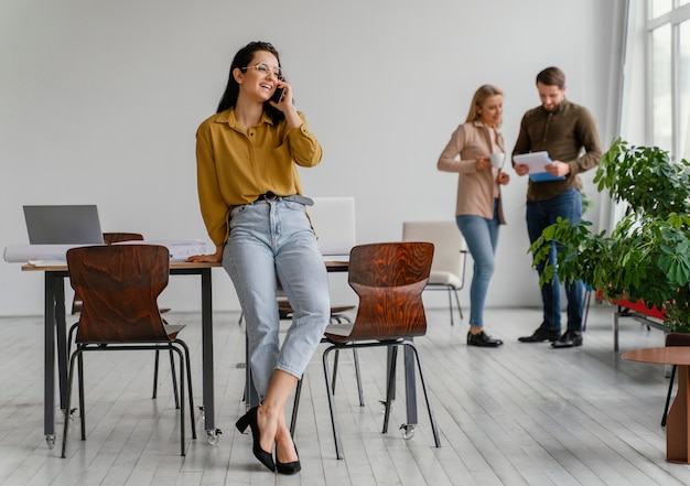 Free photo businesswoman talking on her phone while her teammates are talking