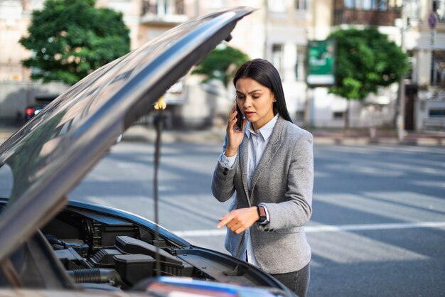 Businesswoman talking on the phone while her car broke down