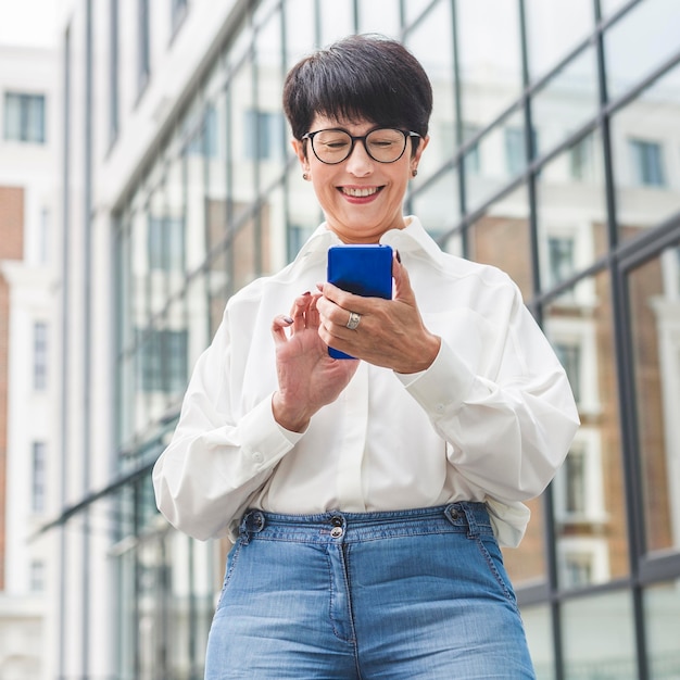 Free photo businesswoman typing on mobile phone low view