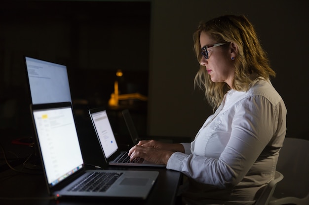 Free photo businesswoman using laptop in dark office