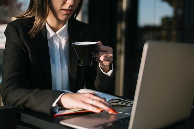 無料写真 一杯のコーヒーを飲みながらラップトップを使用して実業家